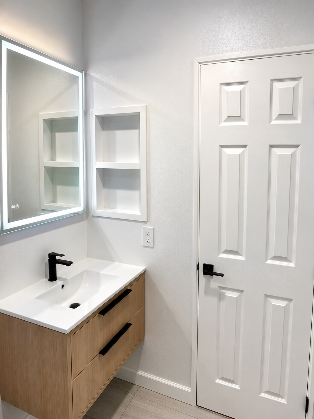 Floating wood vanity with backlit mirror and recessed shelving