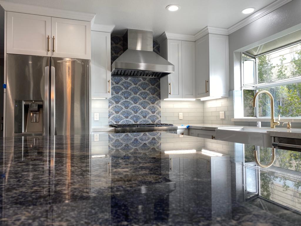 Kitchen remodel with white shaker cabinets, gold hardware, and blue stone island