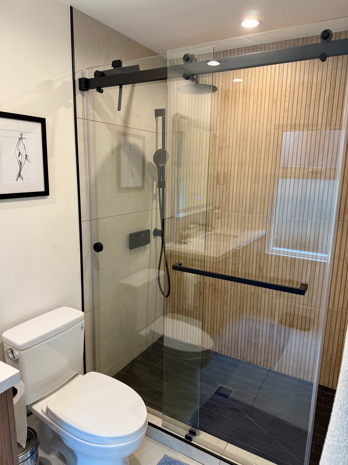 Walk-in shower remodel with wood accent wall and black fixtures