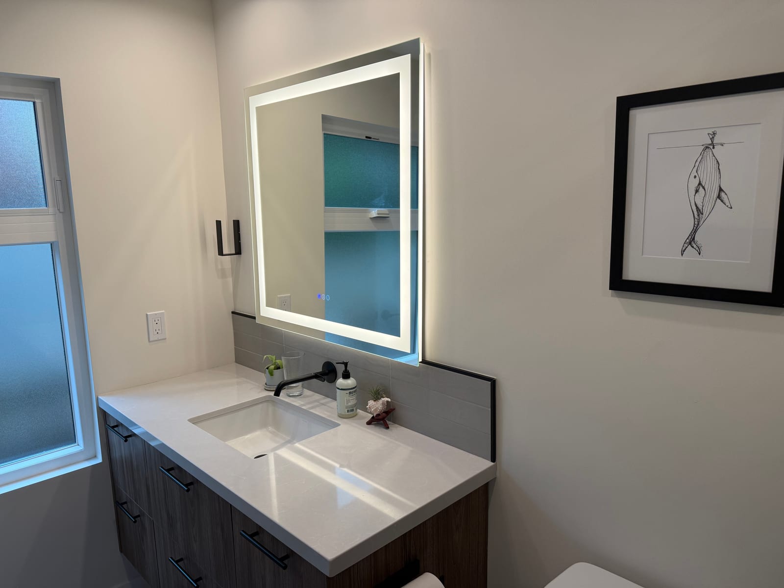 Bathroom vanity remodel with backlit mirror and wall-mounted faucet