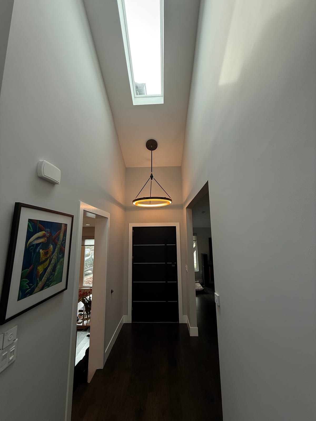 High-ceiling hallway remodel with skylight and pendant light