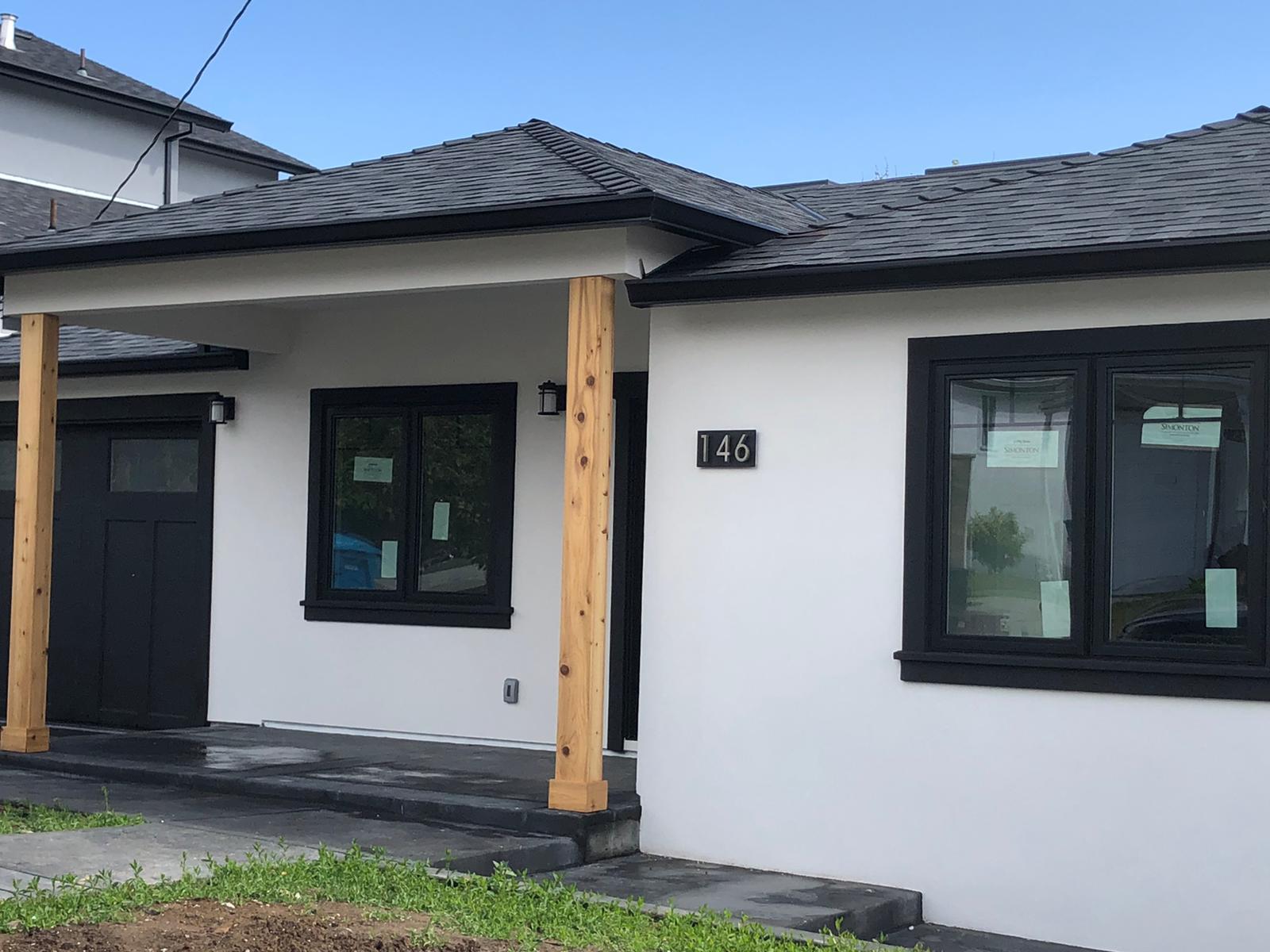 Covered porch entry with cedar posts, black door, and black window trim