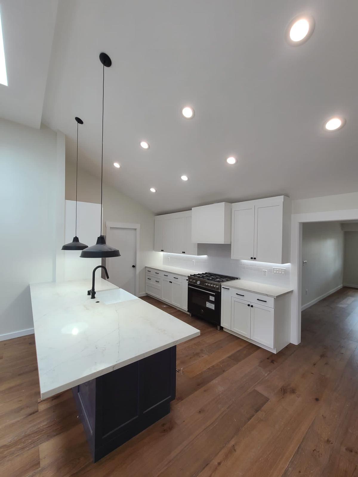Open kitchen with pendant lighting, range wall, and hardwood floors